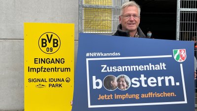 Ein Mann hält ein Schild hoch mit dem Text "Zusammenhalt boostern."