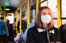 Eine junge Frau trägt eine Mund-Nasen-Schutz-Maske im Bus