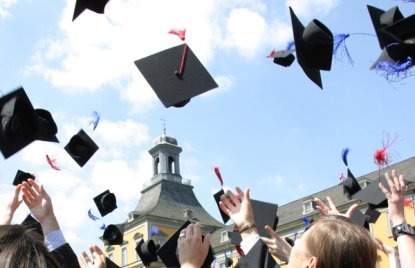 Das Foto zeigt Studierende, die im Rahmen ihres Studienabschlusses bei der Feier ihre Hüte in die Luft werfen.